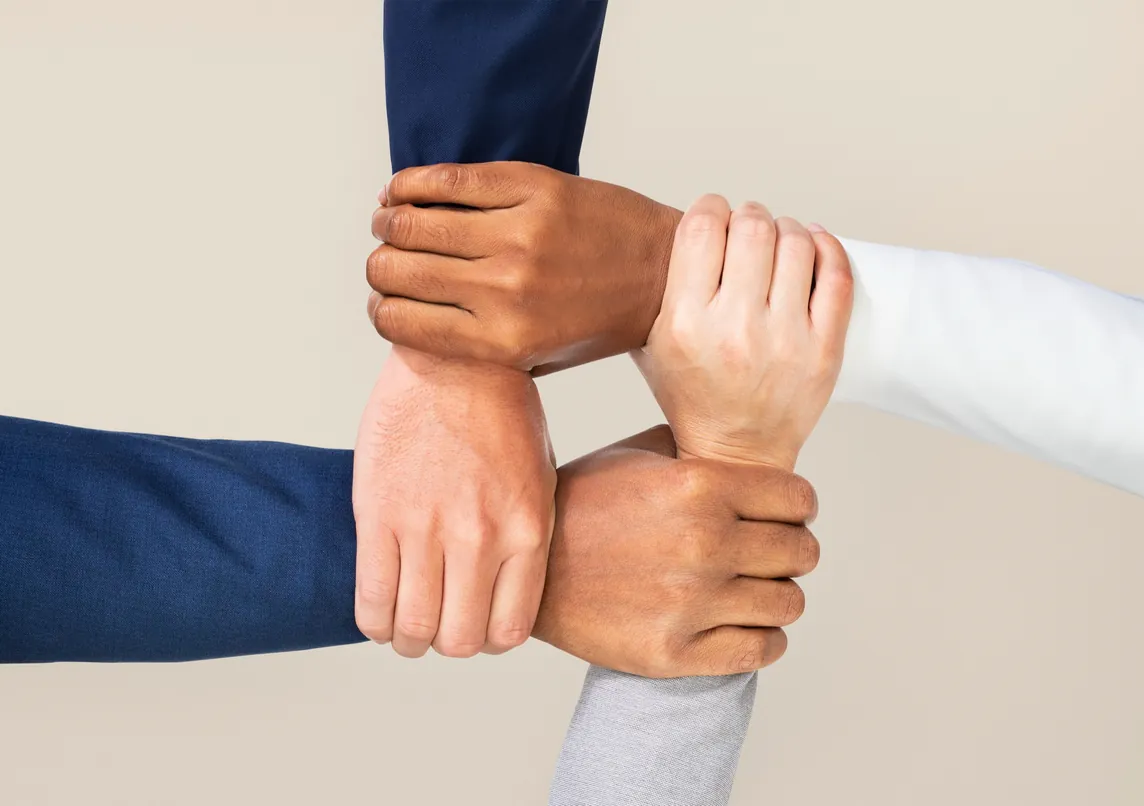 Four people's hands and forearms linked together in a square.